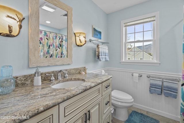 full bathroom featuring vanity, visible vents, a wainscoted wall, tile patterned floors, and toilet