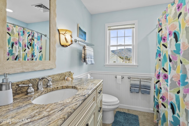 bathroom featuring visible vents, toilet, curtained shower, wainscoting, and vanity