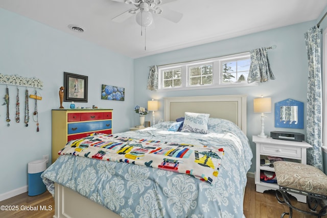 bedroom with a ceiling fan, wood finished floors, visible vents, and baseboards