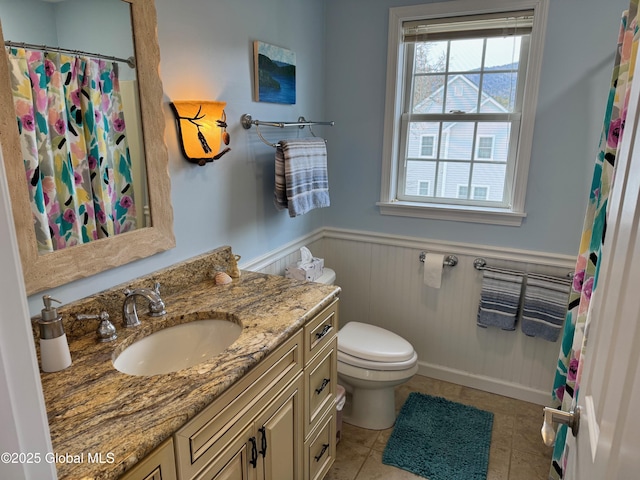 full bath with vanity, a shower with shower curtain, a wainscoted wall, tile patterned flooring, and toilet