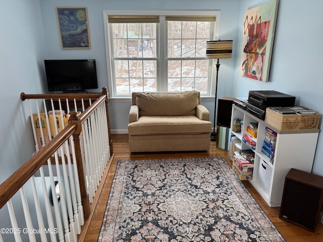 sitting room with an upstairs landing, light wood-style flooring, and baseboards