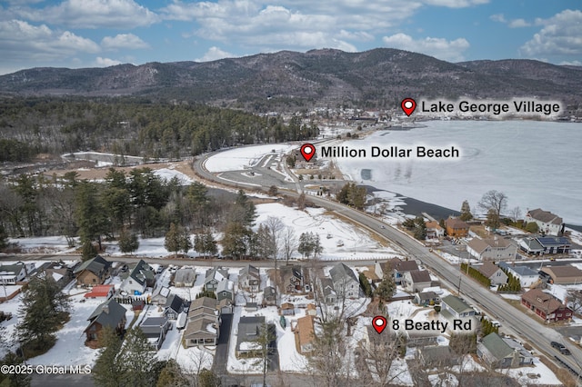 snowy aerial view featuring a mountain view and a residential view