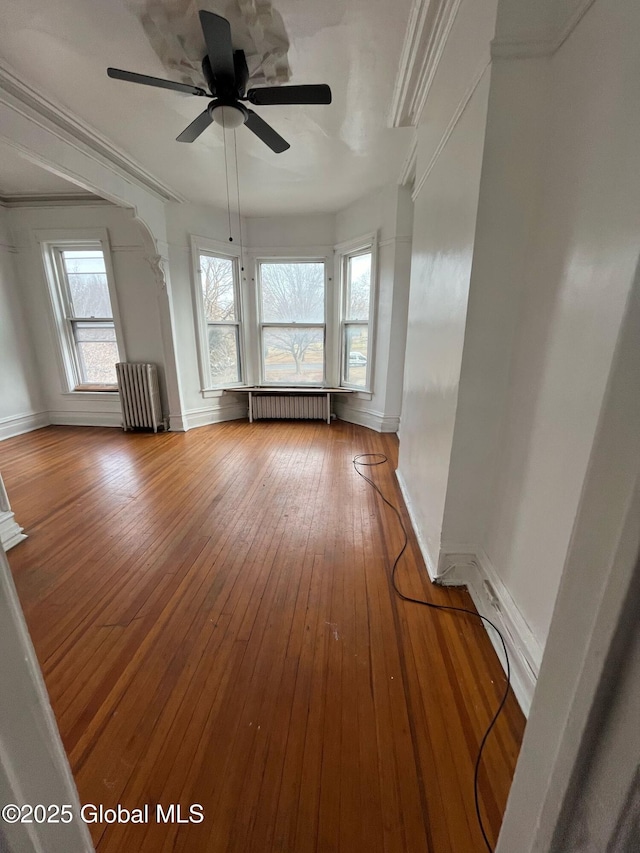 unfurnished room with ornamental molding, radiator, baseboards, and hardwood / wood-style floors