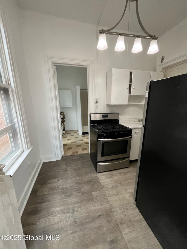 kitchen with baseboards, stainless steel appliances, hanging light fixtures, light countertops, and white cabinets