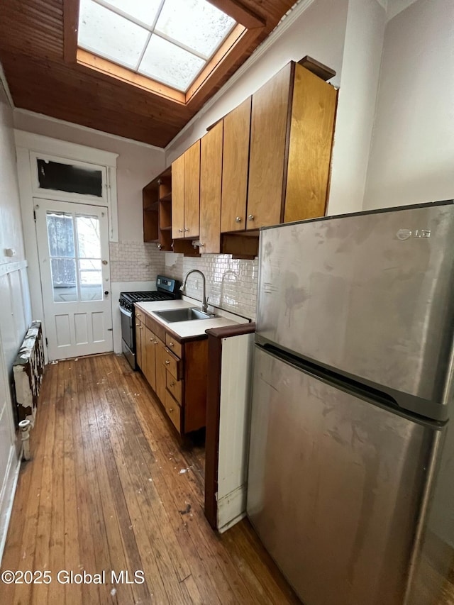 kitchen featuring a sink, backsplash, appliances with stainless steel finishes, a skylight, and open shelves