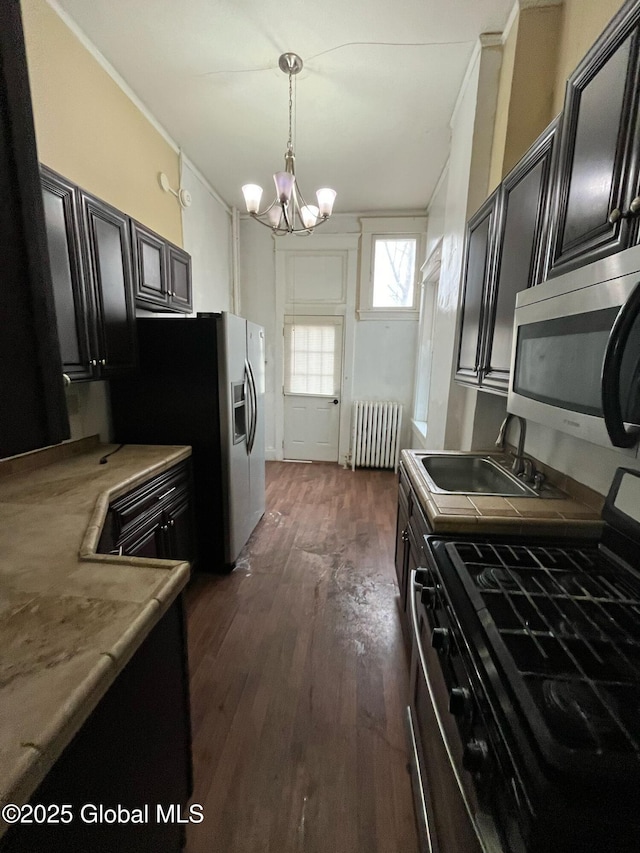 kitchen featuring dark wood-type flooring, a sink, stainless steel appliances, radiator, and dark cabinets