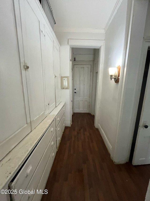 corridor featuring dark wood-type flooring, baseboards, and ornamental molding