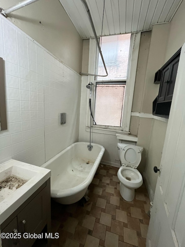 bathroom featuring toilet, vanity, and tile walls