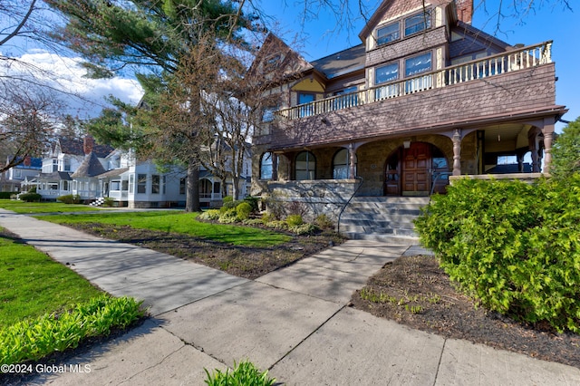 view of front of house featuring a porch, a chimney, and a front yard