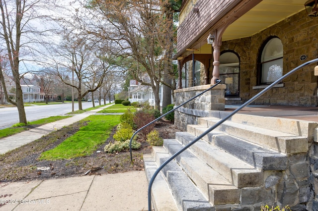 property entrance with a residential view, stone siding, and covered porch