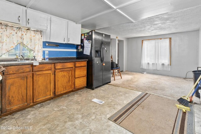 kitchen featuring brown cabinetry, visible vents, a sink, stainless steel refrigerator with ice dispenser, and light carpet