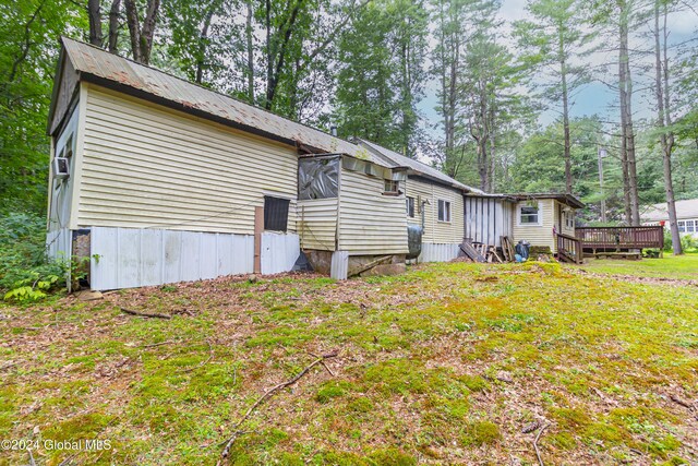 rear view of property with a yard, metal roof, and a deck