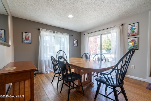 dining room with a baseboard radiator, wood finished floors, baseboards, and a textured ceiling