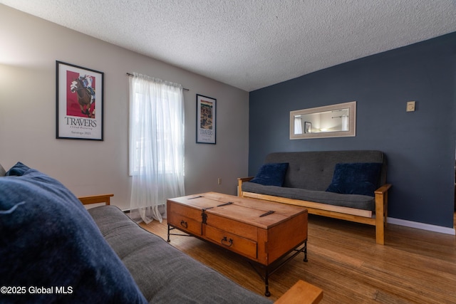 living area featuring wood finished floors, baseboards, and a textured ceiling