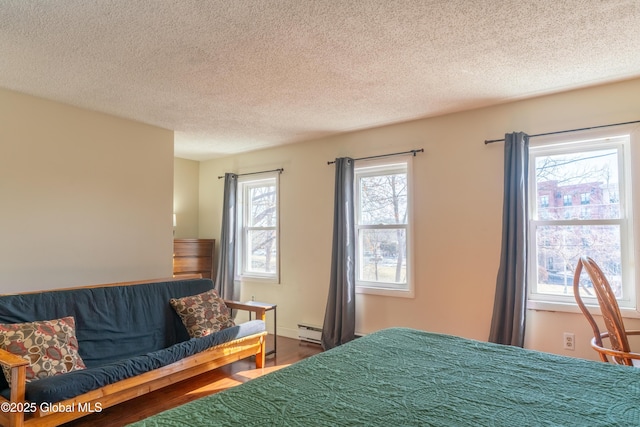 bedroom featuring baseboard heating, a textured ceiling, and wood finished floors