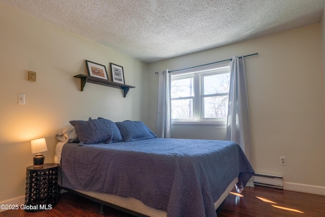 bedroom featuring a textured ceiling, a baseboard heating unit, baseboards, and wood finished floors