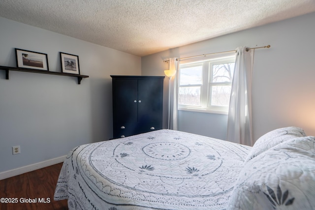 bedroom with dark wood-type flooring, baseboards, and a textured ceiling