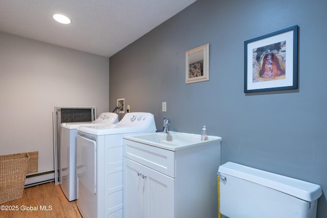 washroom with light wood-type flooring, washing machine and dryer, recessed lighting, a baseboard radiator, and laundry area