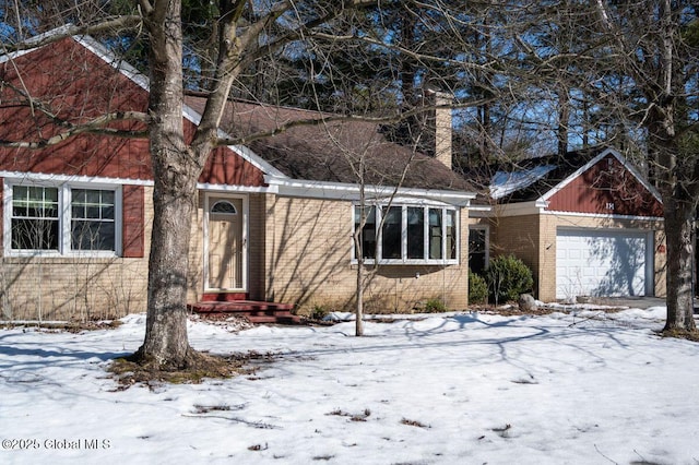 single story home featuring brick siding, a chimney, and an attached garage