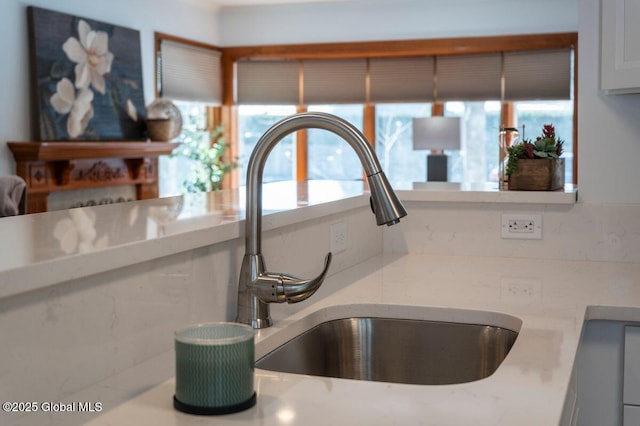 interior details with light stone counters, white cabinets, and a sink