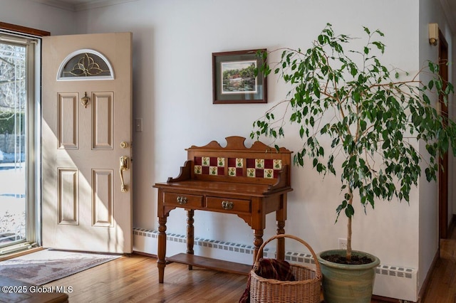 foyer entrance featuring wood finished floors and a baseboard radiator