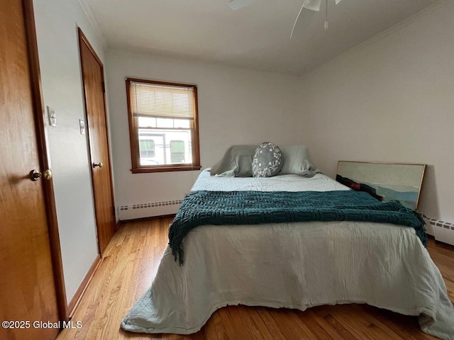 bedroom featuring light wood-type flooring, baseboards, and baseboard heating