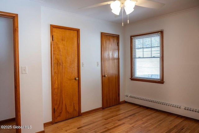 unfurnished bedroom with a baseboard radiator, baseboards, ornamental molding, and light wood finished floors