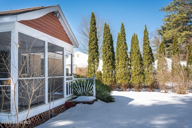 yard covered in snow featuring a sunroom