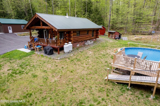 465 Barlow Rd, Bleecker, NY 12078 - back of property with log exterior, a wooded view, a deck, an outdoor pool, and an outdoor structure