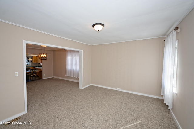 empty room featuring carpet flooring, an inviting chandelier, crown molding, and baseboards