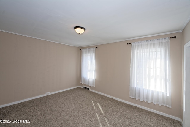 empty room with crown molding, carpet flooring, visible vents, and a wealth of natural light