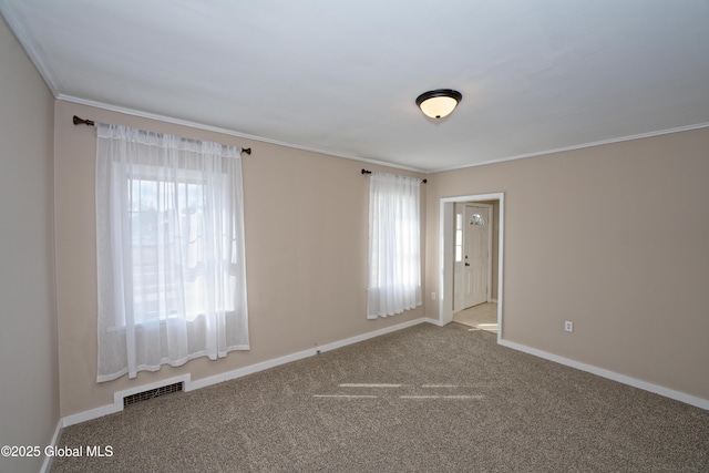 carpeted spare room featuring visible vents, baseboards, and ornamental molding