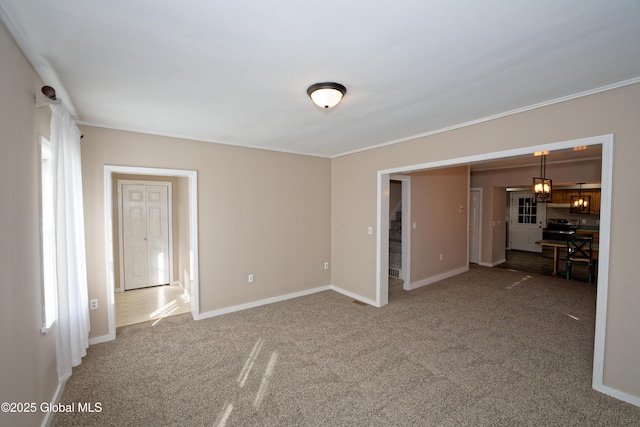 carpeted empty room with crown molding and baseboards