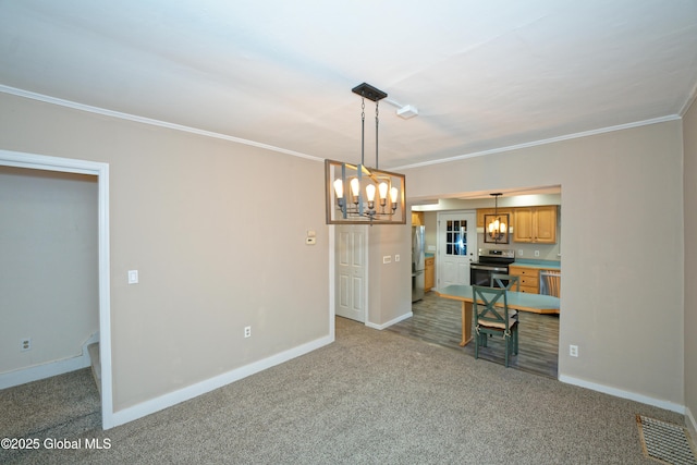 interior space featuring stainless steel appliances, carpet floors, an inviting chandelier, and crown molding