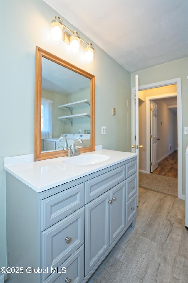 bathroom featuring washer and dryer, vanity, and wood finished floors