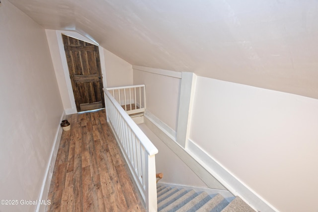 stairway with lofted ceiling, baseboards, and wood finished floors