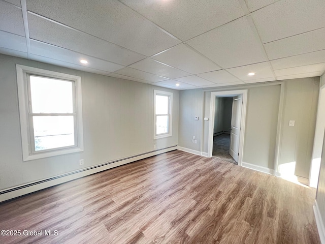 spare room featuring a drop ceiling, wood finished floors, baseboards, and baseboard heating