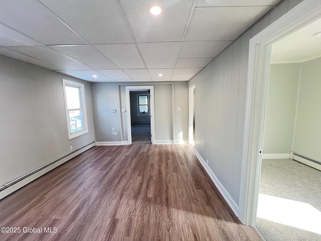 spare room with a drop ceiling, wood finished floors, baseboards, and baseboard heating