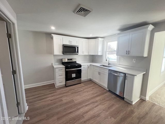 kitchen with wood finished floors, visible vents, a sink, light countertops, and appliances with stainless steel finishes