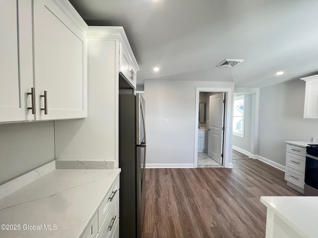 kitchen featuring baseboards, visible vents, freestanding refrigerator, dark wood-type flooring, and white cabinetry