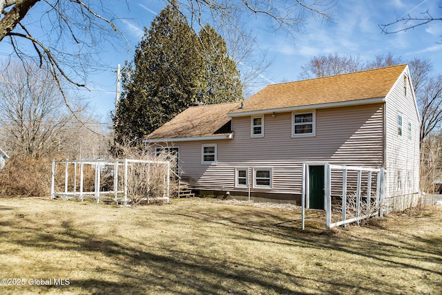 rear view of house with a lawn and roof with shingles