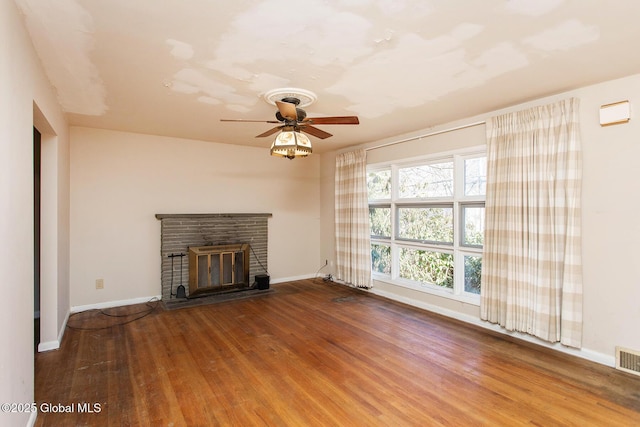 unfurnished living room featuring a fireplace, wood finished floors, baseboards, and a ceiling fan