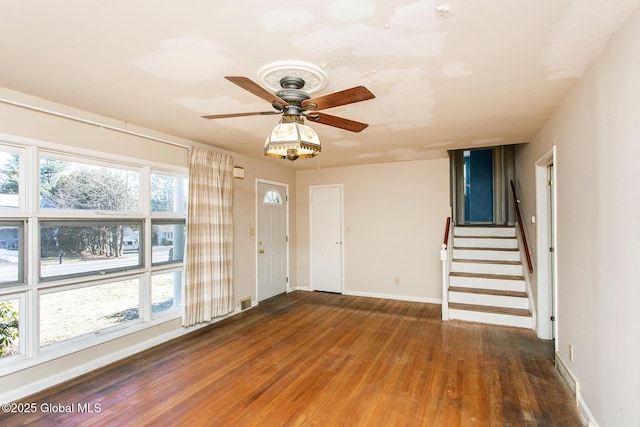 entryway with wood finished floors, visible vents, baseboards, ceiling fan, and stairs