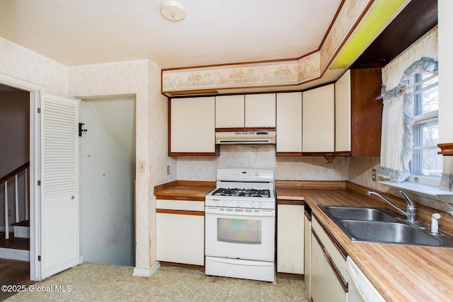 kitchen with wooden counters, under cabinet range hood, white appliances, white cabinetry, and a sink