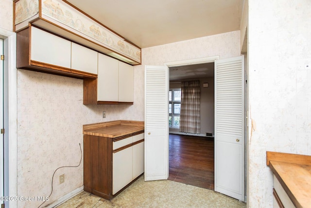 kitchen with visible vents, wallpapered walls, butcher block countertops, light wood-type flooring, and white cabinetry