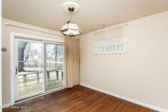 spare room with visible vents, baseboards, and dark wood-type flooring