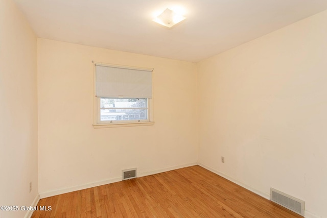 empty room featuring visible vents, baseboards, and light wood-style floors