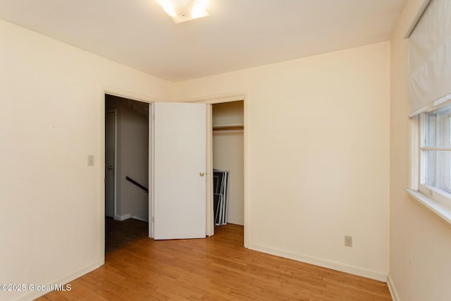 unfurnished bedroom featuring a closet, baseboards, and light wood finished floors