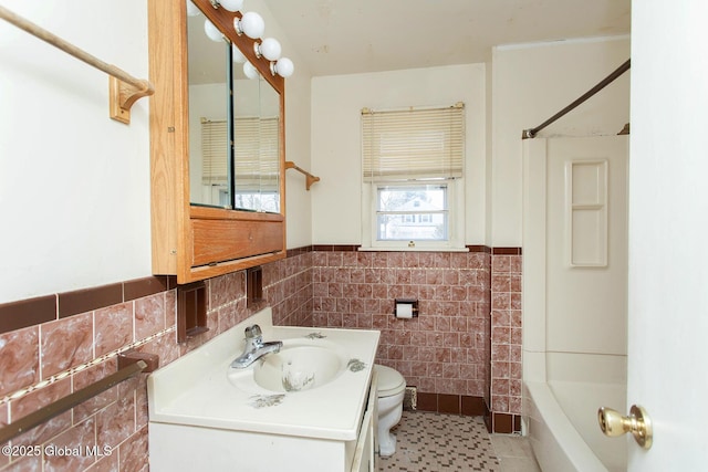 full bath featuring vanity, a wainscoted wall,  shower combination, tile walls, and toilet