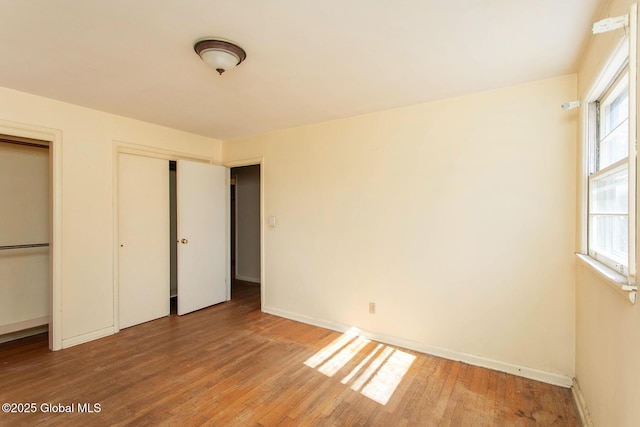 unfurnished bedroom featuring baseboards, two closets, and light wood-style floors